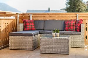 a wicker sofa on a patio with two pillows at Großes Bergapartment 4 SZ Balkon & Aussicht in Sonntag