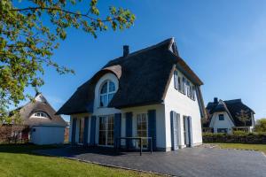 a white house with a black roof at Ferienhaus Schilfrohrsaenger 51 in Fuhlendorf