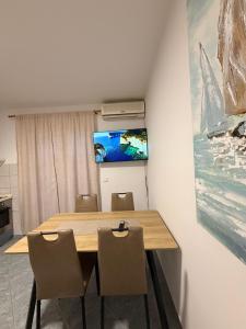 a dining room table with chairs and a television on a wall at Apartmani Gržeta in Vir