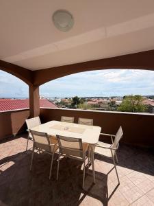 a table and chairs on a balcony with a view at Apartmani Gržeta in Vir