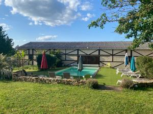 a backyard with a swimming pool with umbrellas and chairs at Les Gîtes de Leymandie in Saint-Avit-de-Vialard