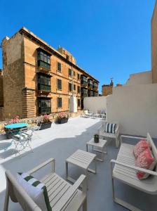 a rooftop patio with chairs and tables and a building at Carmelita in Valletta