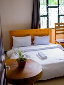 a bed with a wooden headboard and a table at Breezy Lodge in Moshi