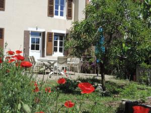 a garden with red flowers in front of a house at Gîte de l'Engièvre in Beaulon