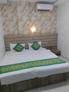 a bedroom with a large white bed with green pillows at Hotel Toss n Sipp Powai in Mumbai