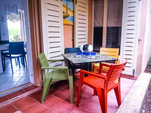 a table with colorful chairs on a porch at Casa di Luga in Costa Paradiso