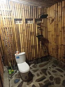 a bathroom with a toilet in front of a bamboo wall at A2 Coconut in Pulau Sarang
