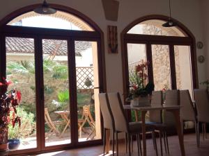 a dining room with a table and two large windows at Can Perles casa rural in Tárbena