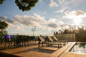 a deck with chairs and a table and a pool at Fazenda Castanheira in Monte Verde