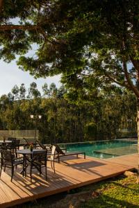 a wooden deck with tables and chairs next to a swimming pool at Fazenda Castanheira in Monte Verde