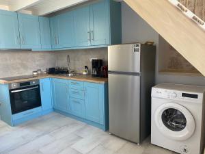 a kitchen with blue cabinets and a washing machine at Fedon in Halki