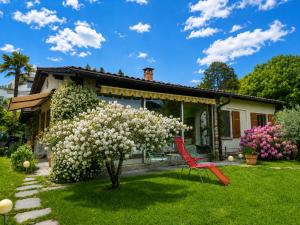 a red chair sitting in front of a house with a flowering tree at Lake View Palm Garden in Lugano