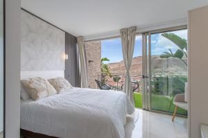 a bedroom with a white bed and a large window at Villa Coco in Mogán +26 photos