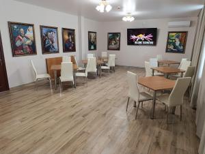 a dining room with tables and chairs and paintings on the wall at Отель Гетьман in Broska
