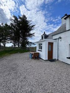 a white house with a picnic table in front of it at Mackenzie Cottage, Kinlochbervie in Oldshore