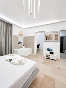 a white bedroom with a bed and a living room at Luxury Way Blue Essence in Molfetta