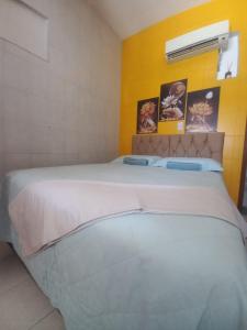 a large white bed in a room with a yellow wall at Aracaju Suite - Wi-Fi, Ar e Ótima Localização in Aracaju