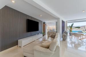 a living room with a couch and a tv on a wall at Villa Coco in Mogán