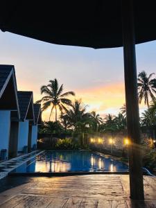 a view of a pool with palm trees at sunset at Bale Bangket Homestay in Tetebatu