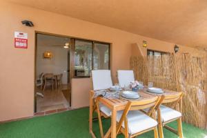 a dining room with a wooden table and white chairs at Oasis Duna _ Casa Mate Pool in Corralejo