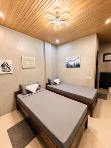 two beds in a room with a ceiling fan at Astra Tourist Inn near Airport with high speed free Wifi in Puerto Princesa City