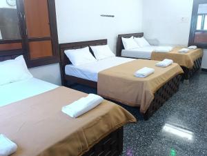 a room with three beds with towels on them at natchiyar home stay in Rāmeswaram