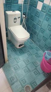 a bathroom with a toilet in a blue tiled floor at natchiyar home stay in Rāmeswaram
