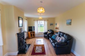 a living room with two leather couches and a fireplace at Montbretia - Ballinskelligs in Dungeagan