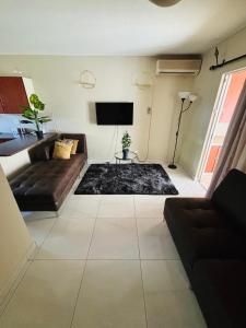 a living room with a couch and a flat screen tv at Sleep in Crestwave villas in eMalahleni