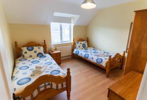 a bedroom with two beds and a window at Montbretia - Ballinskelligs in Dungeagan