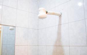 a white tiled shower with a light on the wall at HIDEOUT BnB with swimming pool in Kiambu +12 photos