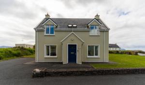 a house with a blue door on a street at Montbretia - Ballinskelligs in Dungeagan