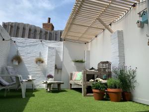 a patio with a wooden pergola and some plants at Kust 3 in Egmond aan Zee