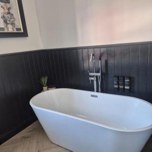 a white bath tub in a bathroom with black tiles at Lochmaben in Lochmaben +17 photos