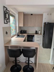 a kitchen with a wooden counter and two bar stools at Apartament Las in Żagań