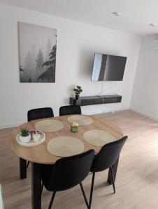 a wooden table in a living room with chairs and a tv at Apartament Las in Żagań