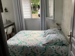 a bedroom with a bed with a flowered blanket and a window at Les clés du temps in Essarts +1 photo