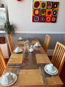 a dining room table with chairs and a painting on the wall at Adelphi Guest House in Douglas