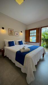 a bedroom with a large bed with blue and white sheets at Pousada Mãe Natureza in Pirenópolis +63 photos