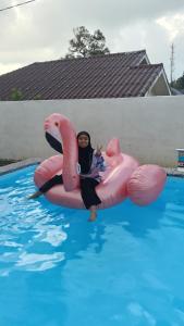 a woman is sitting in a pink flamingo raft in a pool at Rembulan Homestay in Mersing