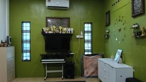 a room with a piano in a green wall at Rembulan Homestay in Mersing +7 photos