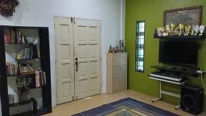 a living room with a piano and a room with green walls at Rembulan Homestay in Mersing