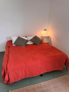 a bedroom with a red bed with two pillows at Studio les Écuries de la forêt 2 in Le Buisson Genois