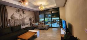 a living room with a couch and a tv at Appartement luxe Taghazout bay - mer & piscine in Agadir