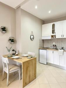 a kitchen with a wooden table and white cabinets at Solis Apartments in Vlorë