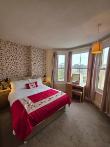 a bedroom with a bed with a red comforter and windows at Rivelyn Hotel Bar & Restaurant in Scarborough