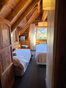 a bedroom with two beds in a log cabin at Hosteria Sudbruck in San Carlos de Bariloche