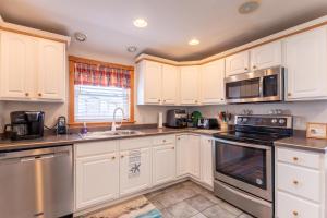 a kitchen with white cabinets and stainless steel appliances at Pelican Watch - Kitty Hawk MP 3, 16 Yards to Beach, Ocean View, Pool, Hot Tub, Pool Table, Flex Stays in Kitty Hawk