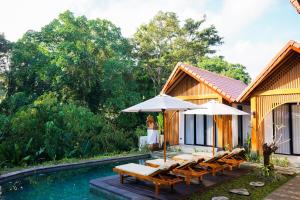 a group of chairs and umbrellas next to a pool at Jisa Sidemen in Sidemen