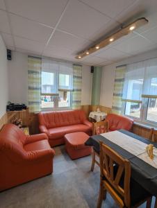 a living room with red leather furniture and a table at Gästehaus Stein im Thüringer Wald in Rottenbach